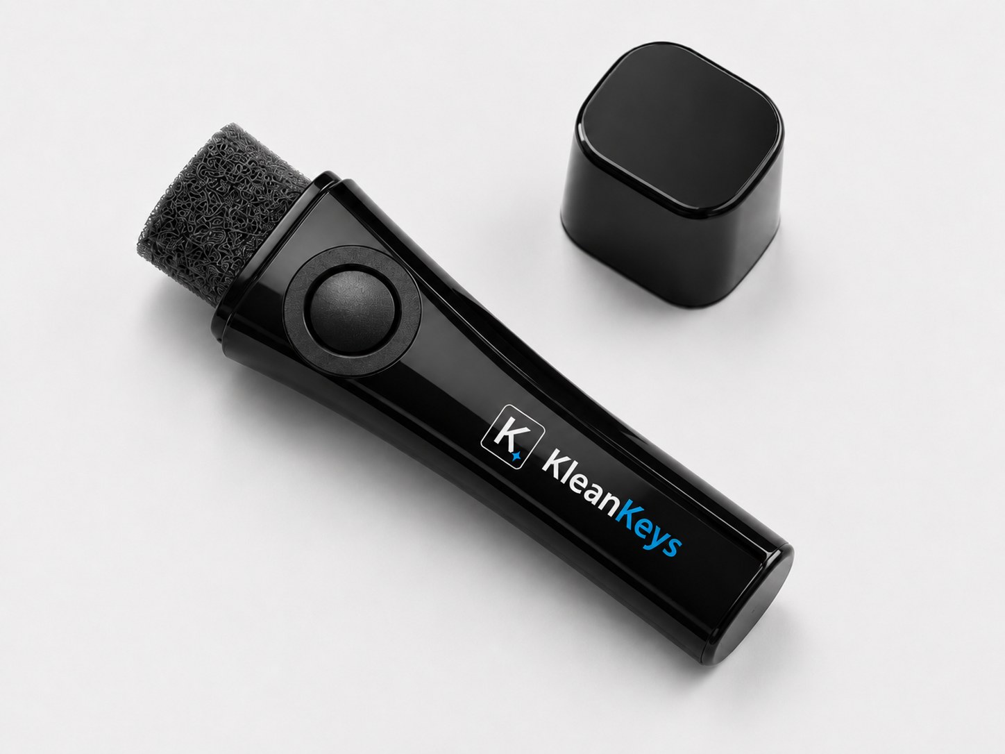 KleanKeys device with cap removed, showing the foam brush tip and logo