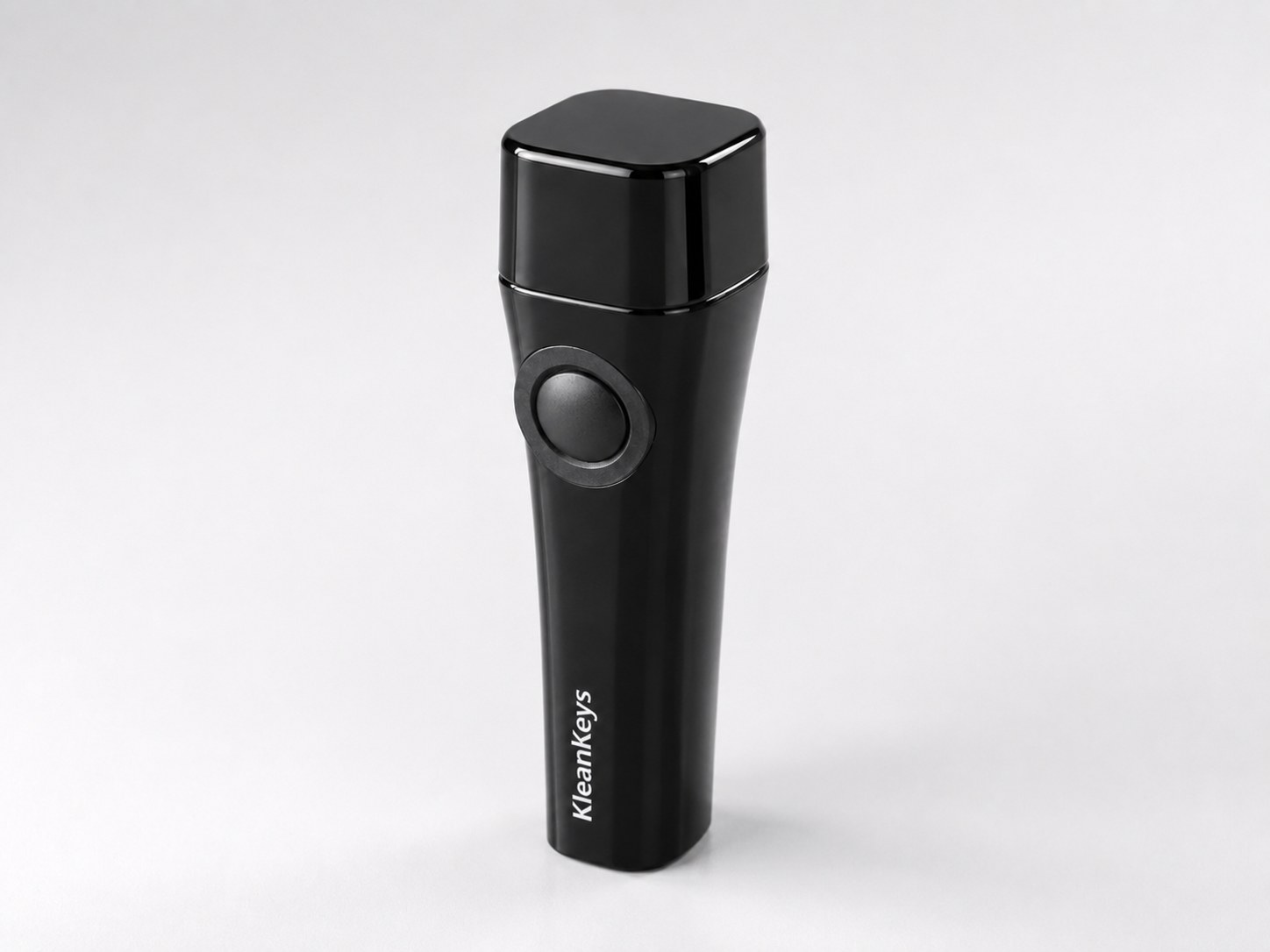 KleanKeys device standing upright, showing the cap, button, and tapered body